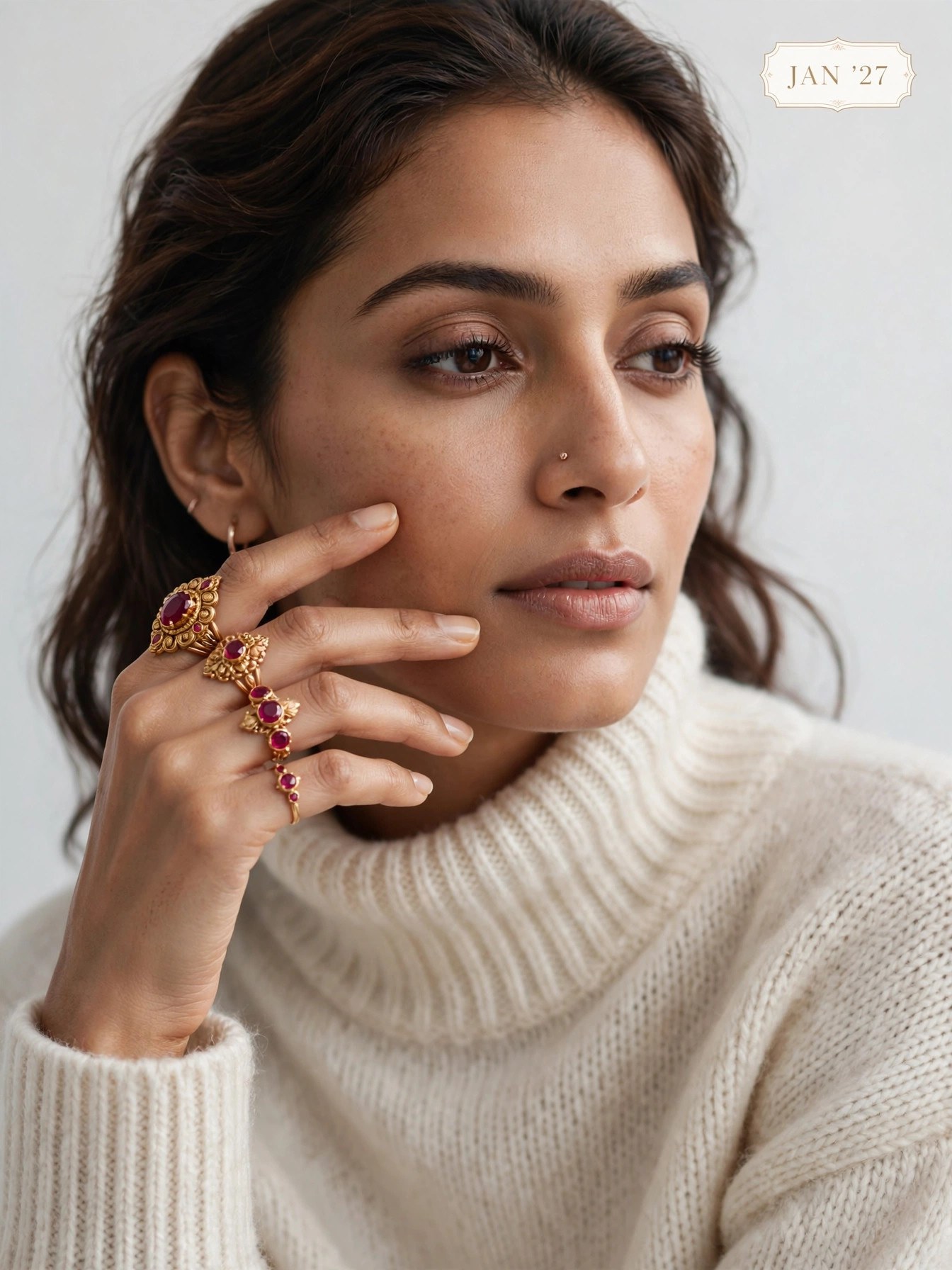 The Swag World Calendar 2027 January Spread - Model wearing handcrafted ruby and gold stack rings with cream knit sweater
