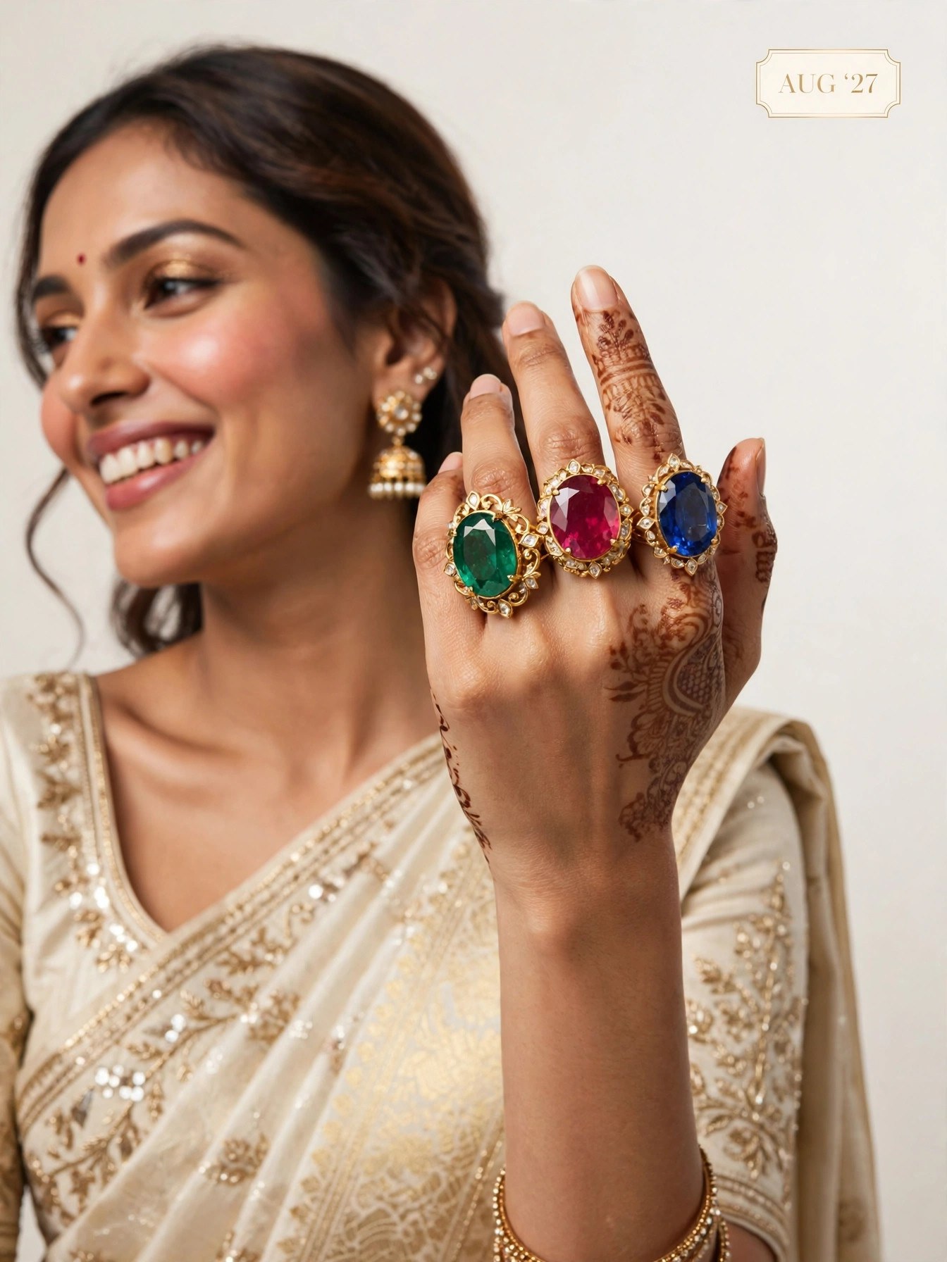 The Swag World Calendar 2027 August Spread - Model showcasing trio of gem cocktail rings on mehendi hand with gold saree